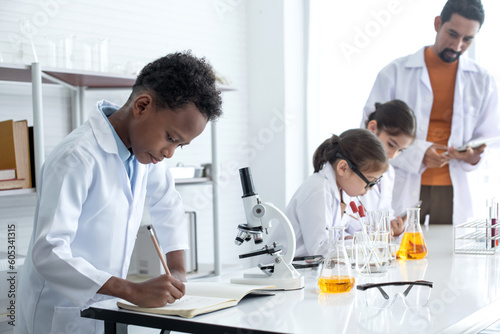 Elementary school classroom, African American boy in Lab coat intend in chemistry class, group of multiethnic kids science lab, selective focus