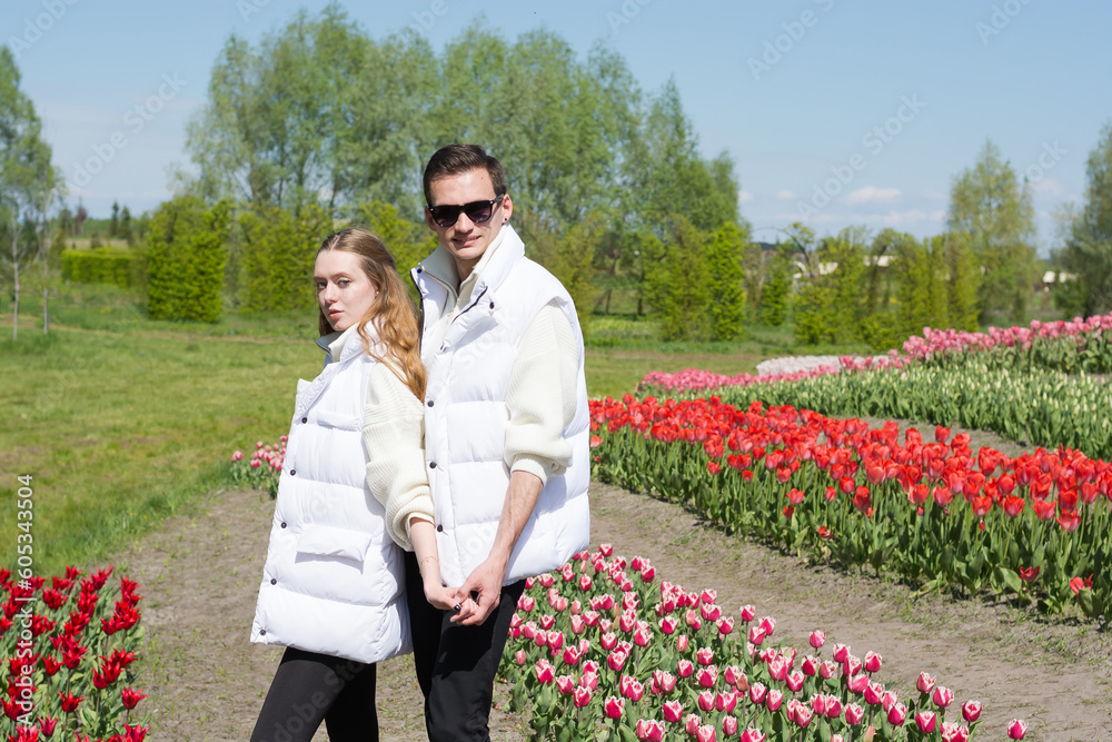 Young beautiful smiling couple on the background of a field of colorful tulips.