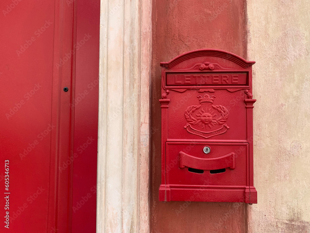 European style red mailbox stuck on a cement wall