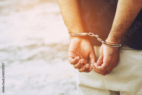 Arrest the offender. Prison male criminal standing in handcuffs with hands behind back. © methaphum