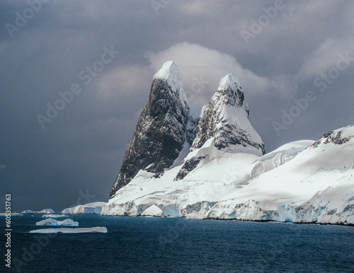 Landscape of snowy mountains and icy shores of the Lemaire Channel in the Antarctic Peninsula, Antarctica. Global warming and climate change concept. photo