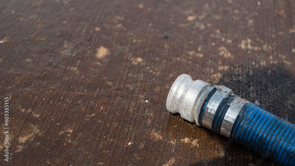 Head of water hydrant hose is laying down on wet cement ground. Industrial equipment object photo. Selective focus. Head of water hydrant hose is laying down on wet cement ground. Industrial equipment object photo. Selective focus.