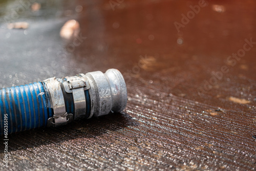 Head of water hydrant hose is laying down on wet cement ground. Industrial equipment object photo. Selective focus.