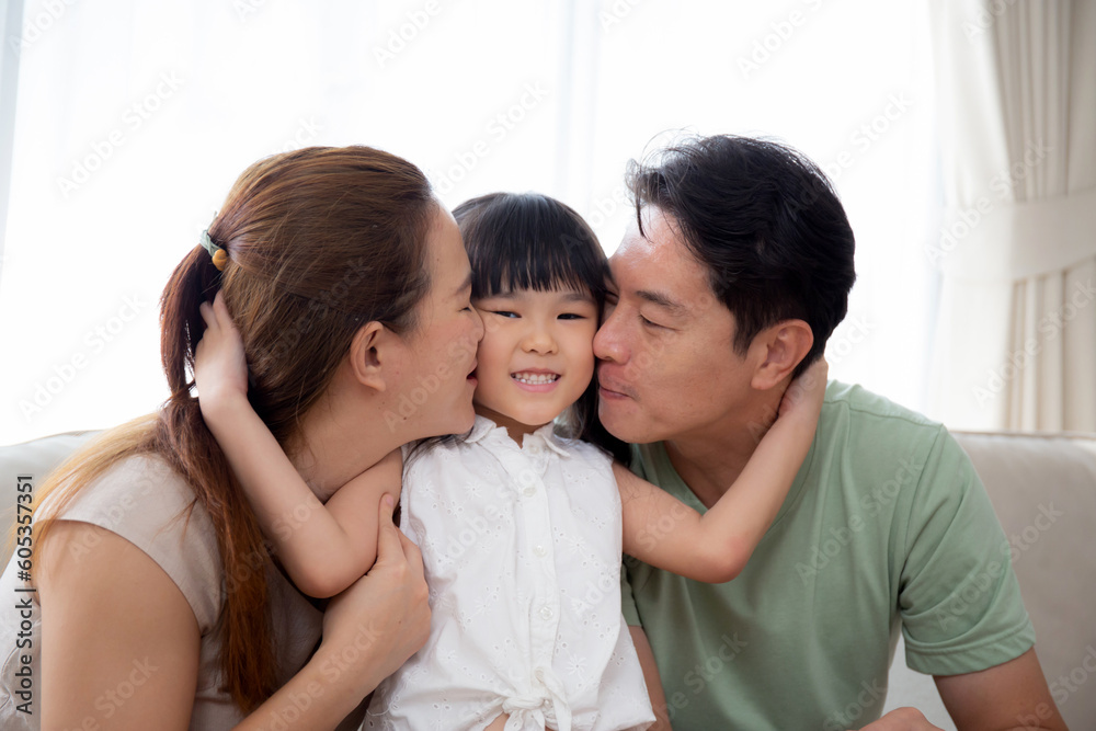 Happy asian family father and mother kiss cheek daughter sitting on sofa in living room at home, dad and mom and kid sitting and relax with comfortable on couch, lifestyles and relation concept. Happy asian family father and mother kiss cheek daughter sitting on sofa in living room at home, dad and mom and kid sitting and relax with comfortable on couch, lifestyles and relation concept.