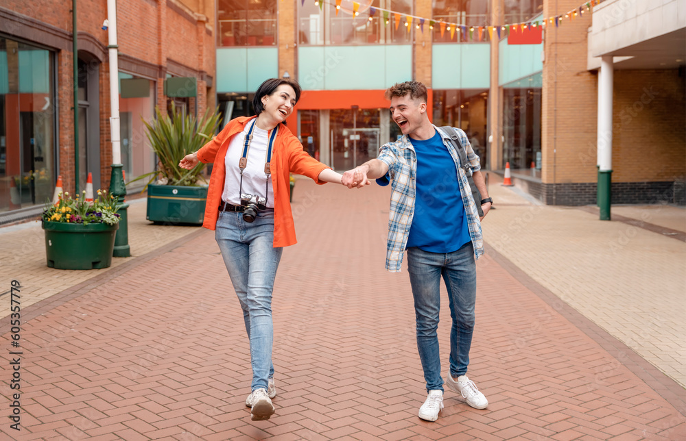 Obraz premium two friend, couple using a camera, taking selfie against a red phonebox, watching photos on camera, having a fun in the city of England.Travel Lifestyle concept