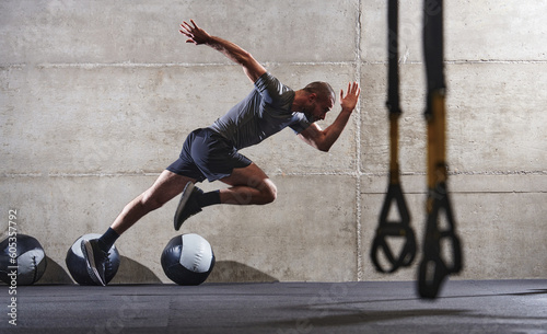 A muscular man captured in air as he jumps in a modern gym, showcasing his athleticism, power, and determination through a highintensity fitness routine