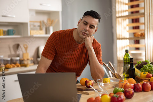 A homely and healthy male prepares nutritious diet  including variety of fruits. Following cooking show on laptop Mastery of peeling  chopping  and slicing fruits to prepare them in artistic style.