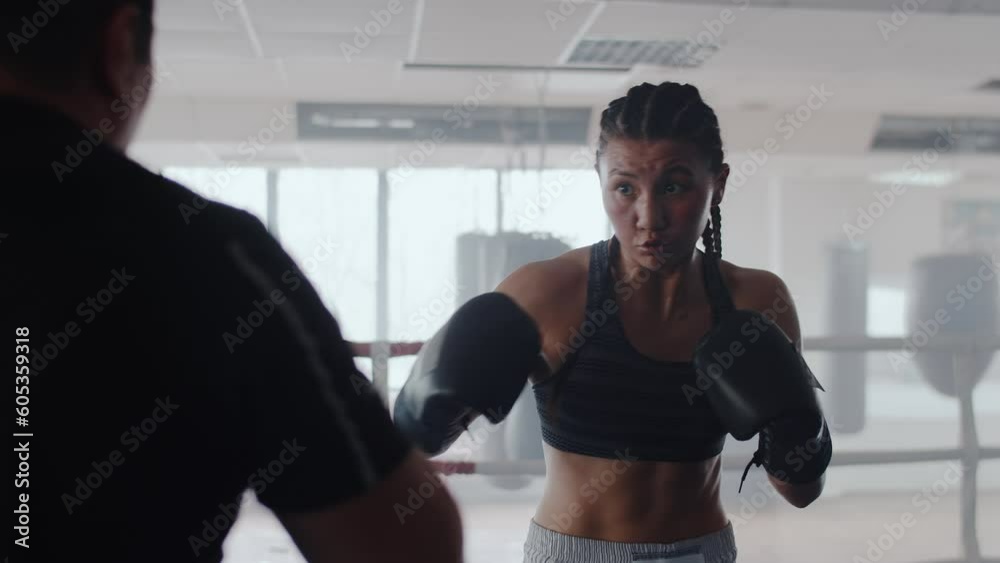 Young asian female boxer in gloves delivers a series of strong and ...