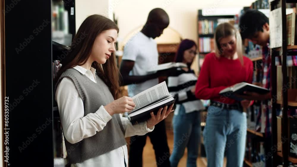 Woman student with long hair in college library read book. Smart and thoughtful young female student read book standing in university library, side view Woman student with long hair in college library read book. Smart and thoughtful young female student read book standing in university library, side view