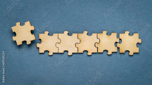 row of wooden jigsaw puzzle on blue background, completing a task or solving a problem concept