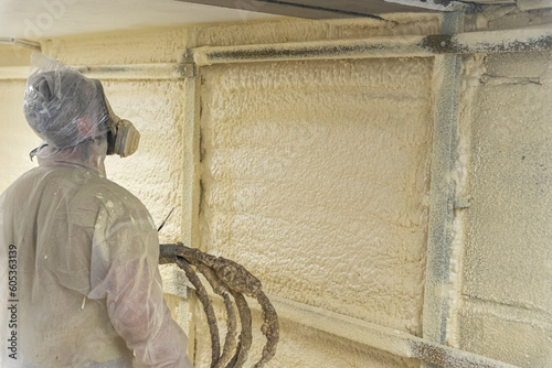 worker in a protective suit insulates the walls with polyurethane foam