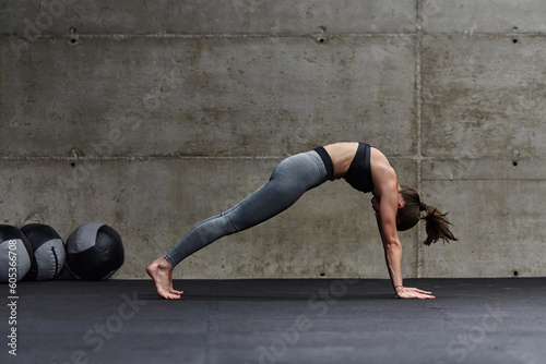 Fit woman in a modern gym working flexibility and strength through various exercises, demonstrating her commitment to fitness