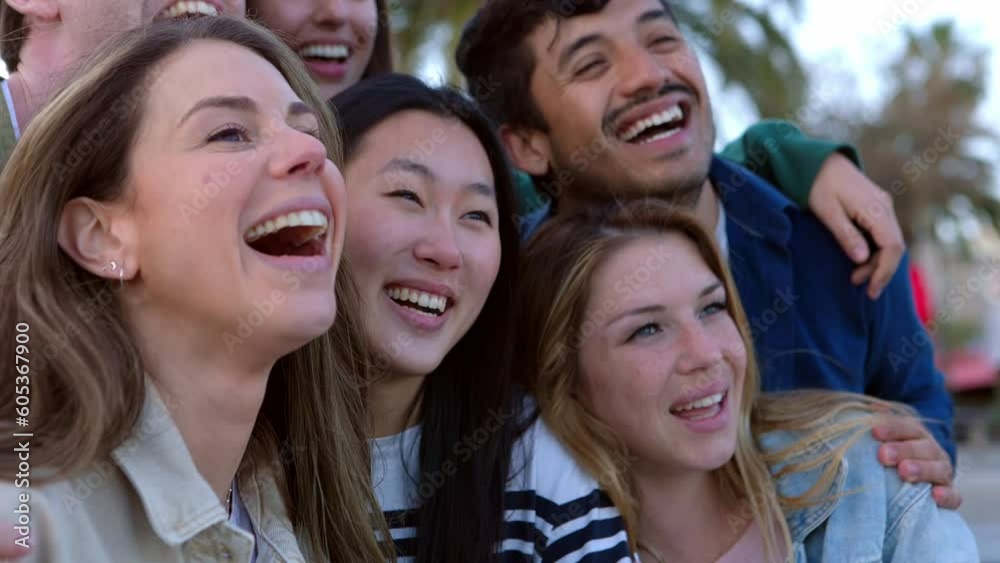 Happy young group of student friends laughing together outdoors. Multiethnic millennial people having fun enjoying day off in city street. Social meeting and youth community concept.