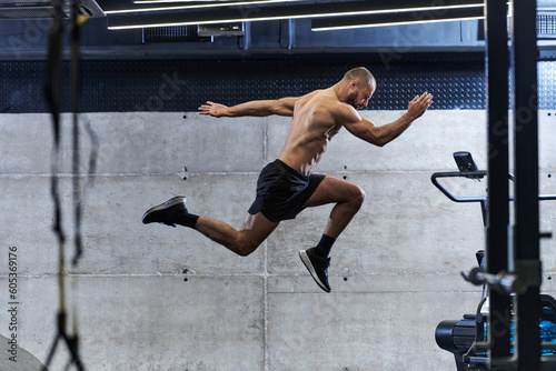 A muscular man captured in air as he jumps in a modern gym, showcasing his athleticism, power, and determination through a highintensity fitness routine © .shock