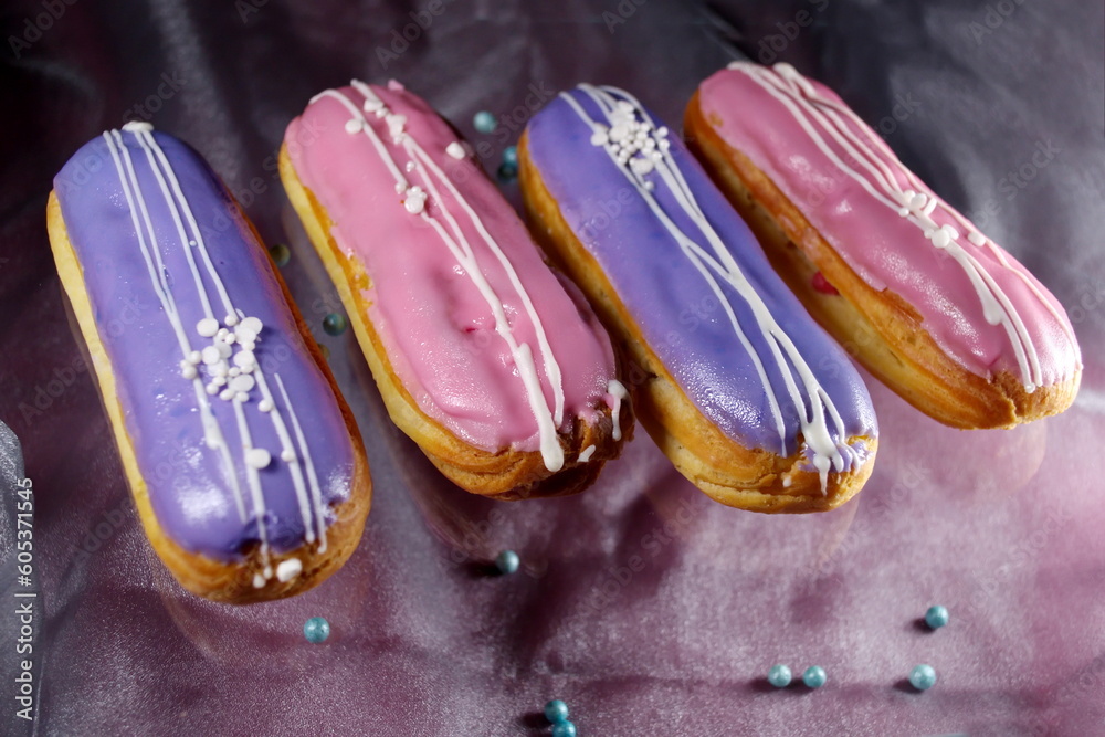 Fototapeta premium french dessert Eclair cake with pink violet creme shining decoration Filling and glaze with strawberries and blueberries Silver organza background effect of levitation Place for text elegant dessert