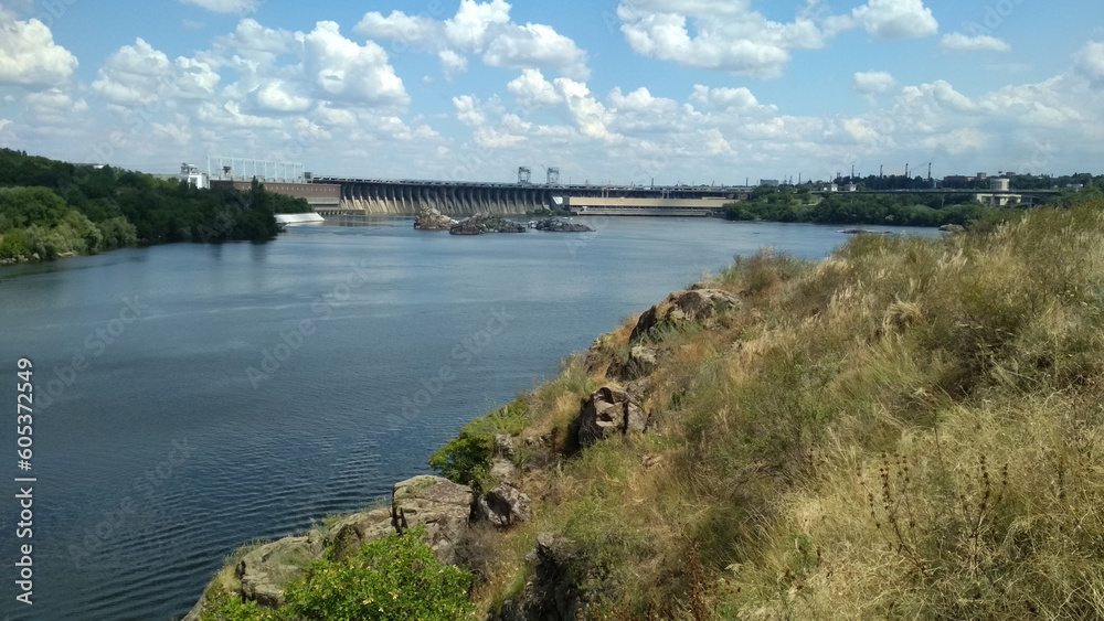 Blue water of Dnipro river before russians blew up Kakhovka Dam, Zaporizhzhia, Ukraine. Hydro electric power station, Dniprohes. Rocky shore, Khortytsia island. Sunny summer day. Blue water of Dnipro river before russians blew up Kakhovka Dam, Zaporizhzhia, Ukraine. Hydro electric power station, Dniprohes. Rocky shore, Khortytsia island. Sunny summer day.