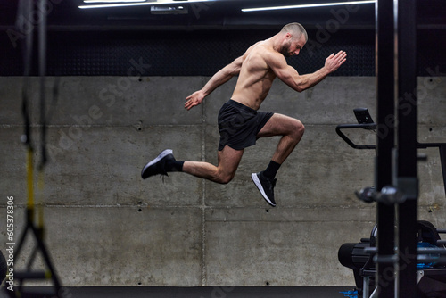 A muscular man captured in air as he jumps in a modern gym, showcasing his athleticism, power, and determination through a highintensity fitness routine
