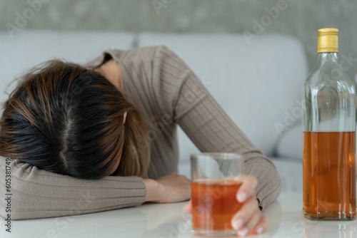 Depressed young Asian woman addicted feeling bad drinking whiskey alone at home, stressed frustrated lonely drinking alcohol suffers from problematic liquor, alcoholism, life and family problems