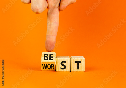 Best or worst symbol. Businessman turns wooden cubes and changes the word best to worst. Beautiful orange table orange background, copy space. Business and best or worst concept.
