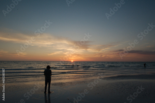 Sunset dark at Florida beach. Calm water with yellow sky from sun. Silhouette of person looking towards sunset.