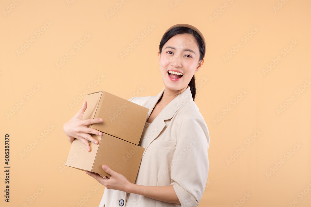 portrait of happy successful confident young asian business woman wearing white jacket holding parcel box isolated on beige studio background, Delivery courier and shipping service concept. portrait of happy successful confident young asian business woman wearing white jacket holding parcel box isolated on beige studio background, Delivery courier and shipping service concept.