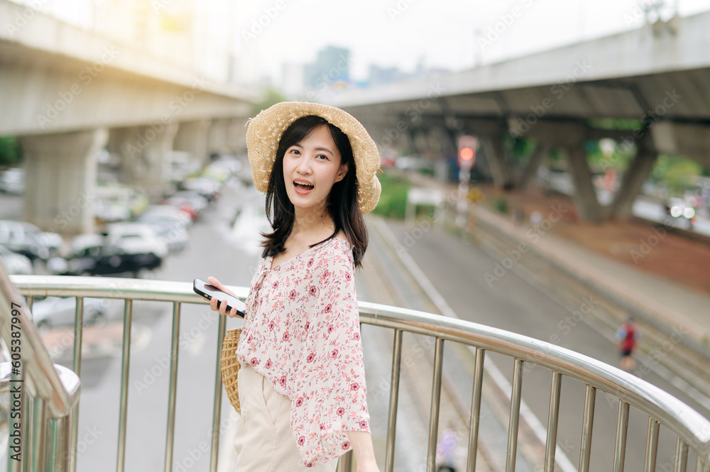young asian woman traveler with weaving basket using mobile phone and standing on overpass with railway background. Journey trip lifestyle, world travel explorer or Asia summer tourism concept. young asian woman traveler with weaving basket using mobile phone and standing on overpass with railway background. Journey trip lifestyle, world travel explorer or Asia summer tourism concept.