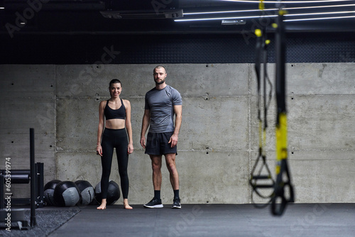Muscular man and fit woman in a conversation before commencing their training session in a modern gym.