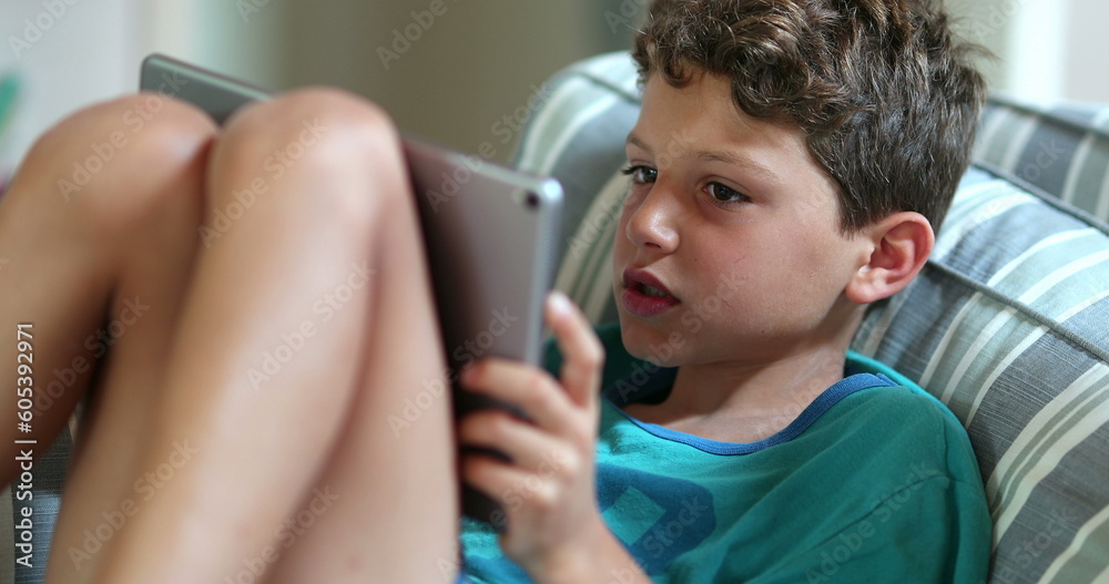 Child hypnotized by game, kid playing using tablet device Child hypnotized by game, kid playing using tablet device