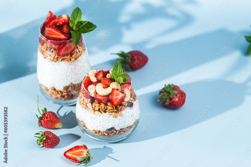 Granola with yogurt, chia and strawberries in a glass on a bright background Granola with yogurt, chia and strawberries in a glass on a bright background