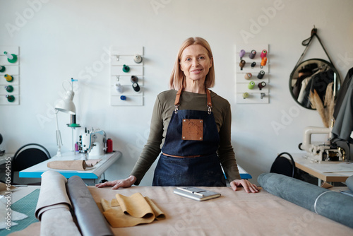 Photography Smiling mature craftswoman in apron looking at camera in workshop or studio whil