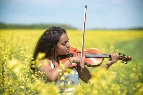 Lovely black woman playing violin in a rapeseed field