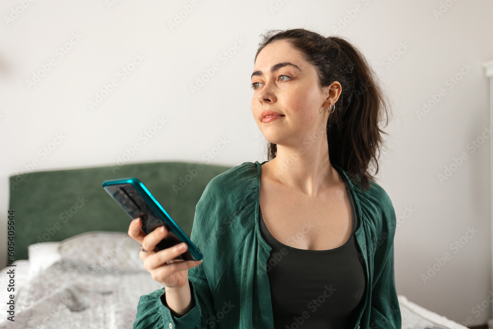 Portrait of young Caucasian woman using smartphone sitting on bed. Concept of online casino game and social media. Portrait of young Caucasian woman using smartphone sitting on bed. Concept of online casino game and social media.