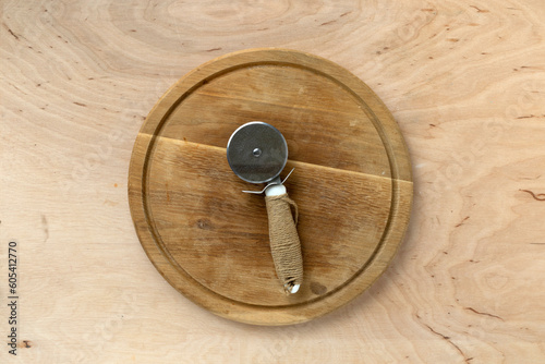 Round wooden pizza board and pizza cutter, copy space, top view