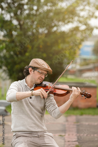 man composing music in the park playing a violin