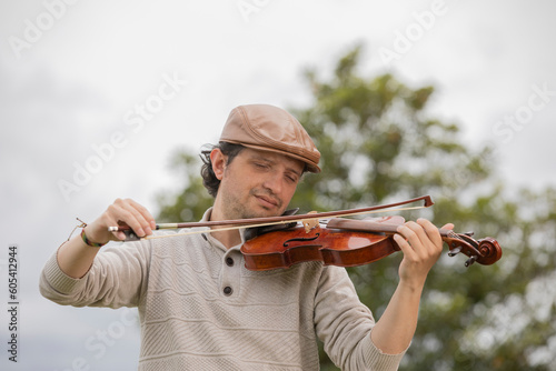 man composing music in the park playing a violin