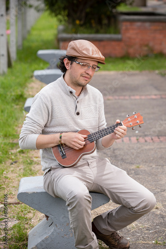 man composing music in the park playing a ukulele