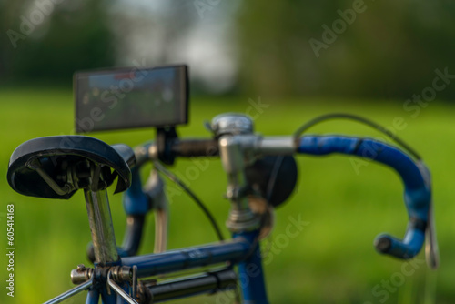 Old bicycle with very modern mobile phone on handlebar on spring color meadow photo