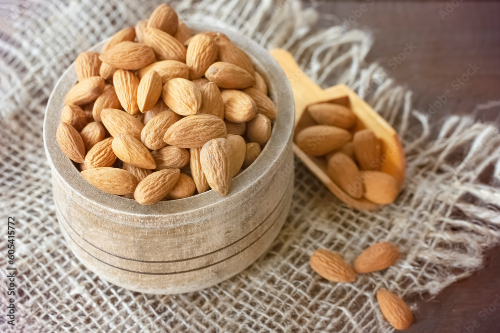 almond seeds in a wooden bowl and spoon on the table close-up. almond top view close-up. background with raw almonds. almond seeds in a wooden bowl and spoon on the table close-up. almond top view close-up. background with raw almonds.