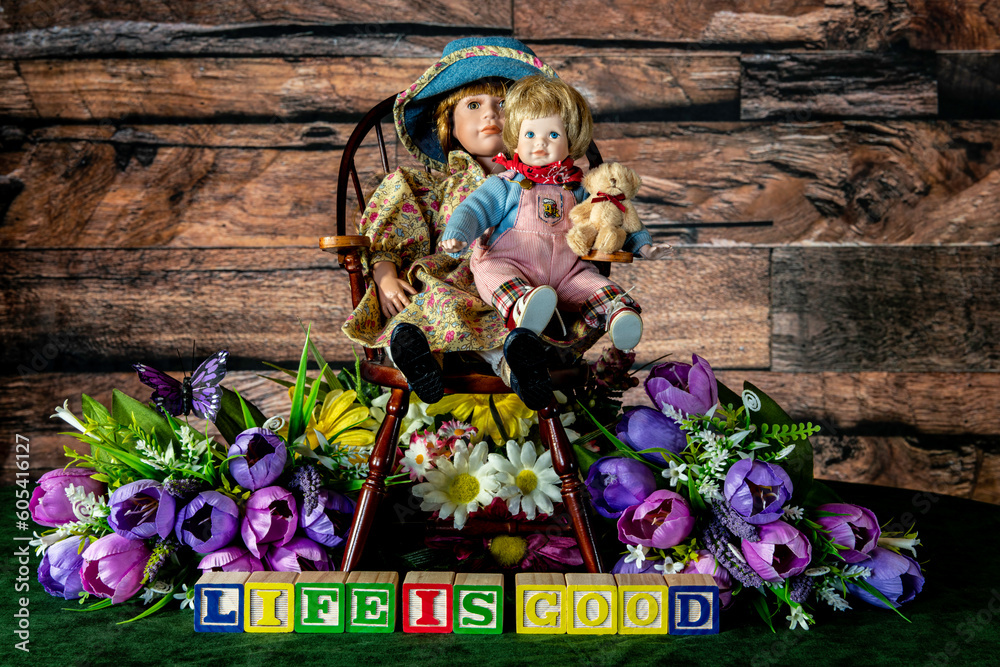 life is good spelled with wood blocks with flowers and child dolls