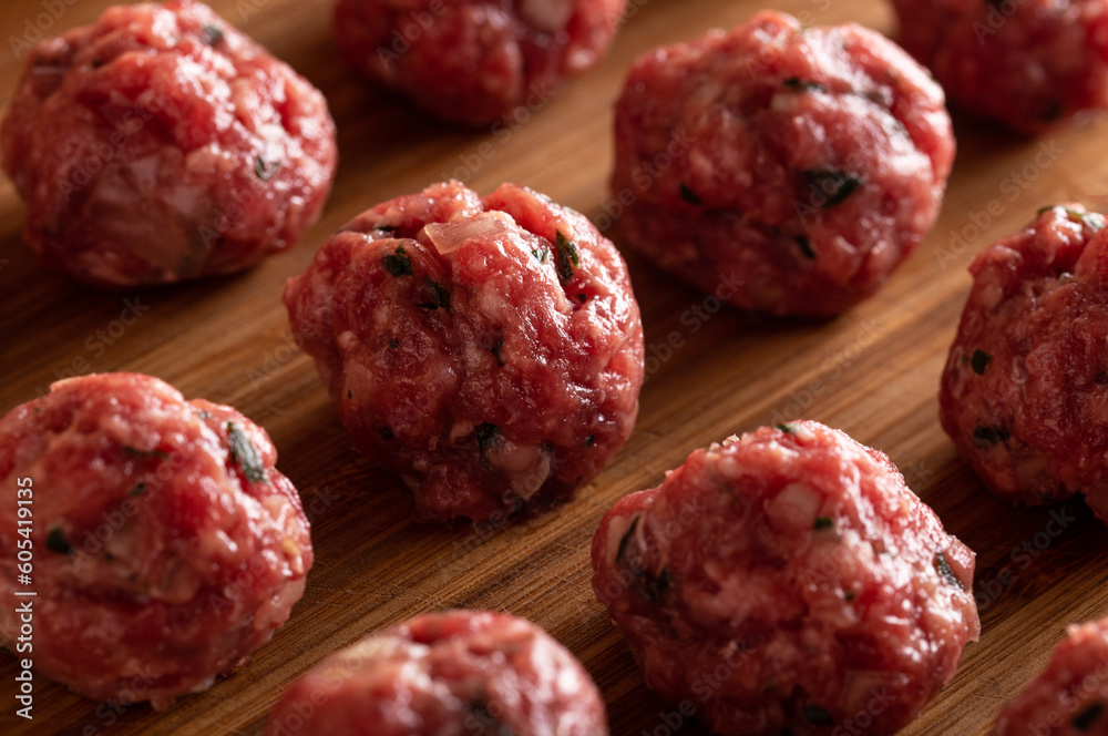 Raw uncooked meatballs on wooden cutting board. Raw uncooked meatballs on wooden cutting board.