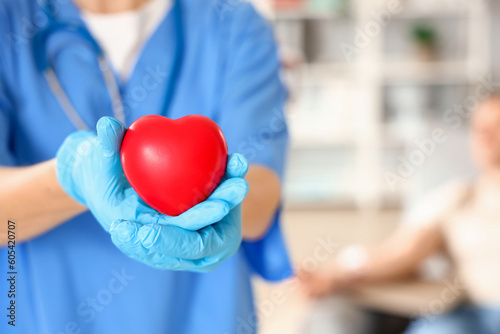 Female nurse with heart in clinic, closeup