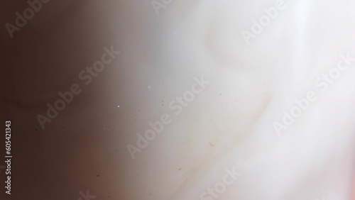 Close-up process of making latte, cappuccino, pouring milk, cream into transparent glass cup with coffee. Abstract white background.Mixing of liquids. Hot caffeine drinks.