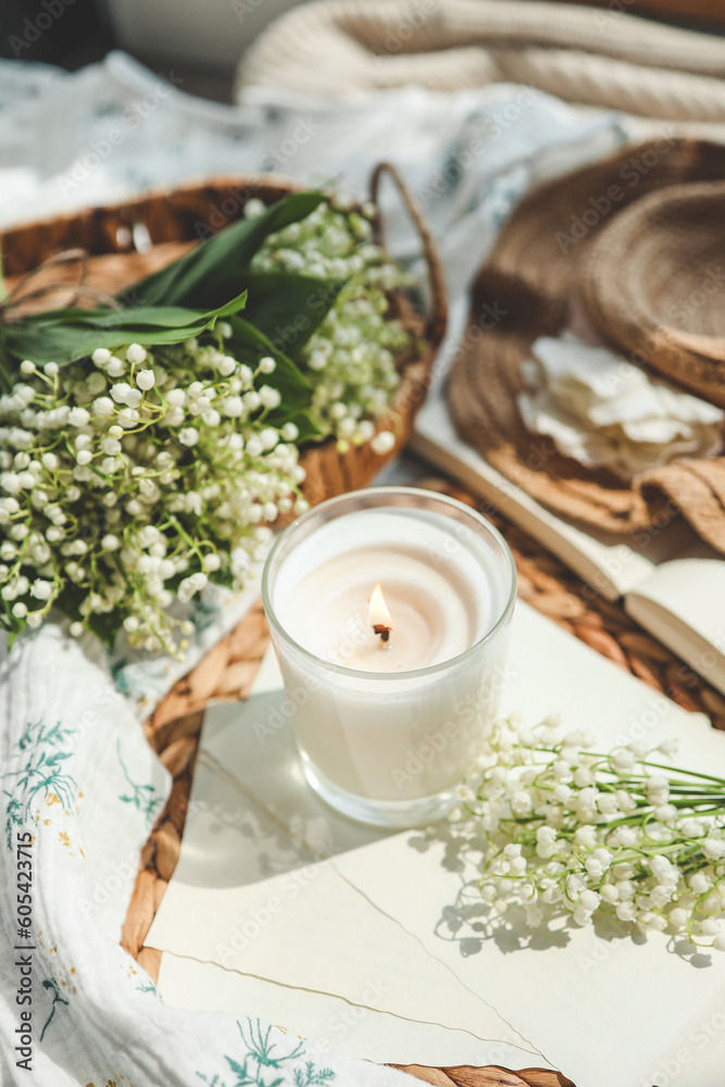 A white burning candle and a bouquet of lilies of the valley, a natural spring photo A white burning candle and a bouquet of lilies of the valley, a natural spring photo