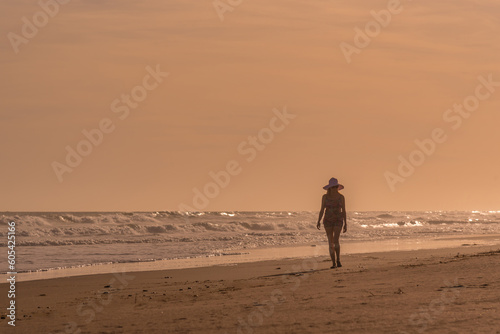 Woman relaxing while walking alone on the beach.