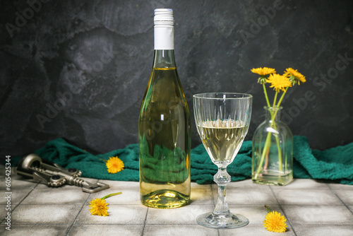 Bottle and glass of dandelion wine on grey tile table