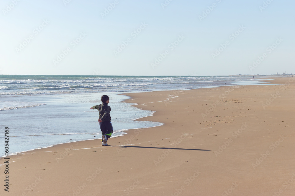 Little boy playing and running on the beach.
