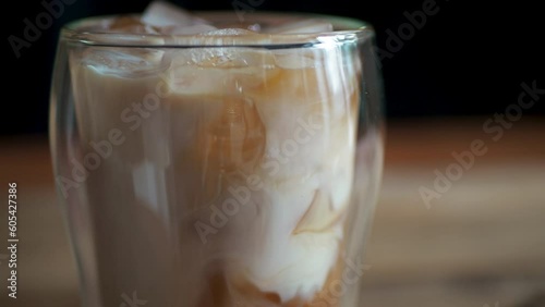 Ice coffee in a tall glass and pouring milk from above close-up.Cold summer drink.