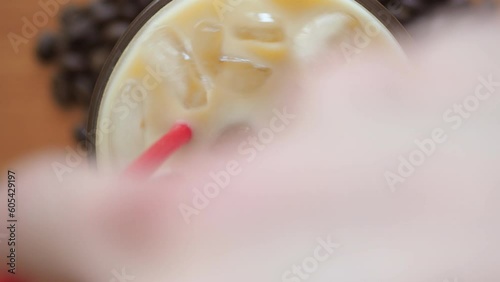 a man mix a glass of iced coffee with red straw, coffee beans on the table.Cold summer drink.Above close up view flatlay.