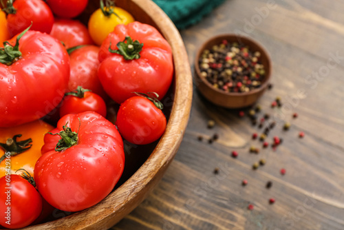 Bowl with different fresh tomatoes on wooden background