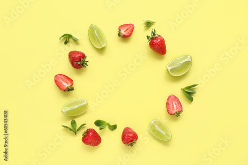 Frame made of fresh strawberries with lime and mint on yellow background